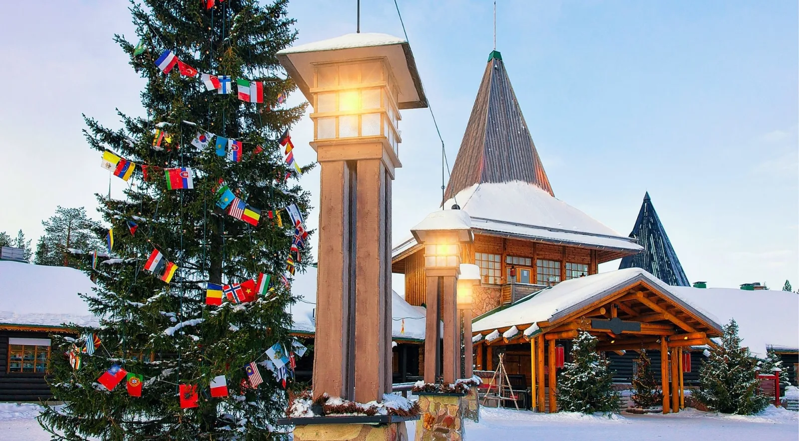 Snow-covered entrance to Santa Claus Village with an international-flag Christmas tree